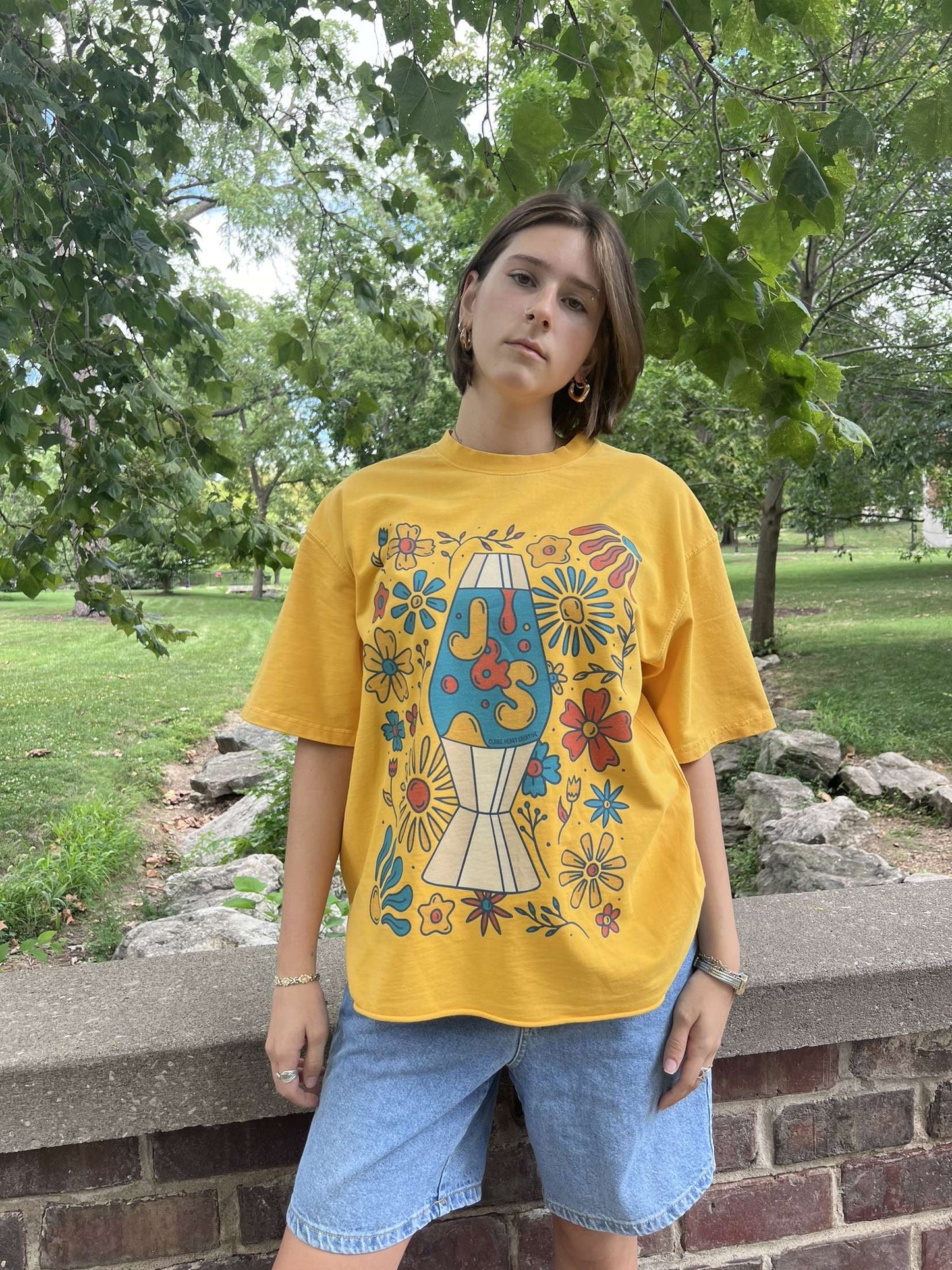 A model wearing the yellow JOHNSONANDSCOTT and Claire Henry Creative collaboration shirt outdoors.